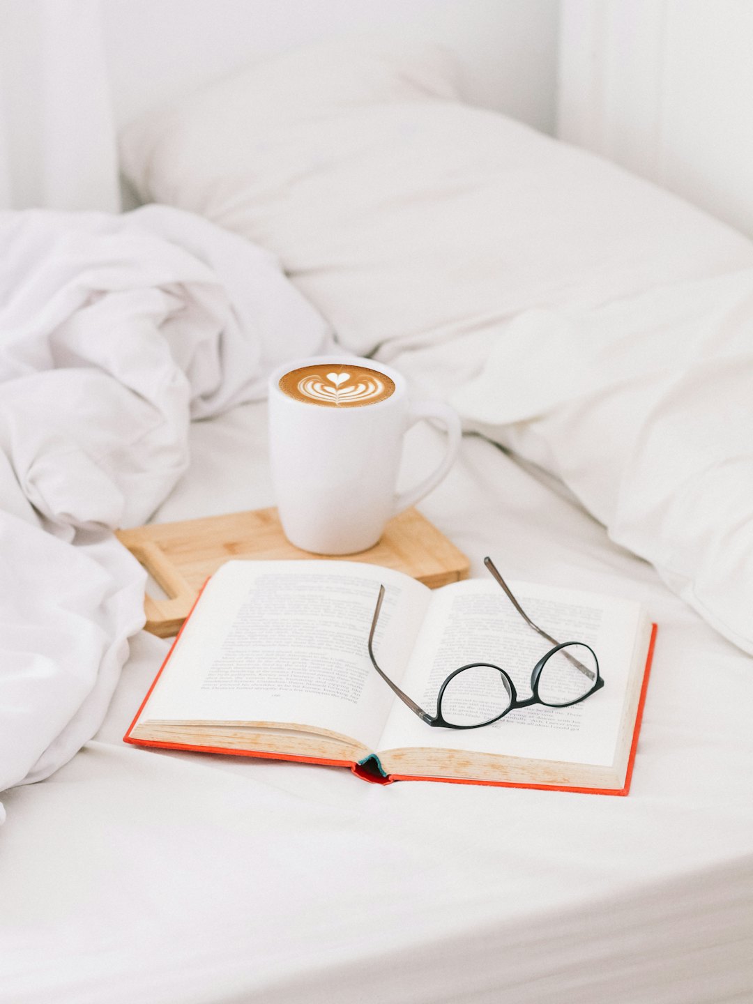 Brille auf einem offenen Buch neben einem Latte.